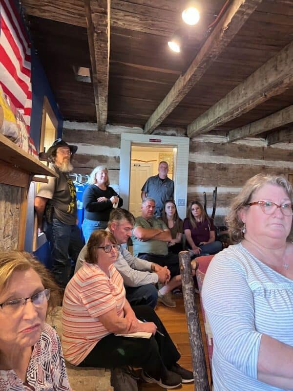 A group of people listening at a meeting in a rustic building.