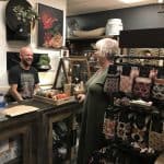 A shopkeeper and a customer share a laugh in a small store packed full of interesting home wares.