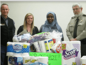 A diverse group of people with a pile of toilet paper packages
